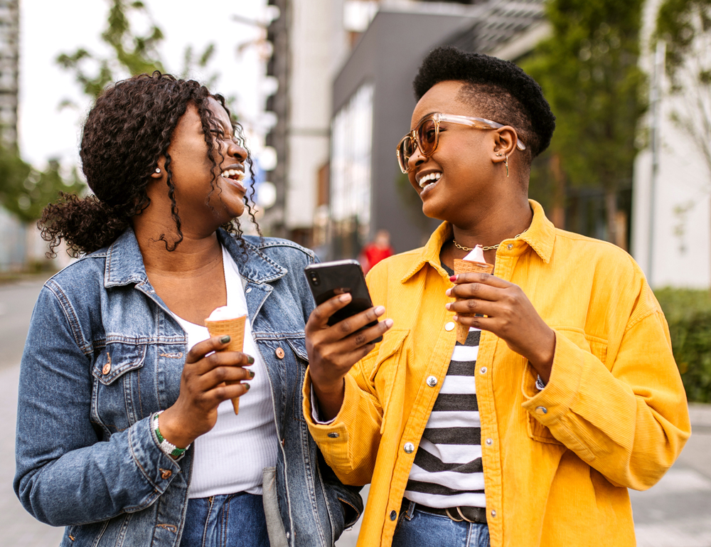Two people laugh and talk as they walk along a street.