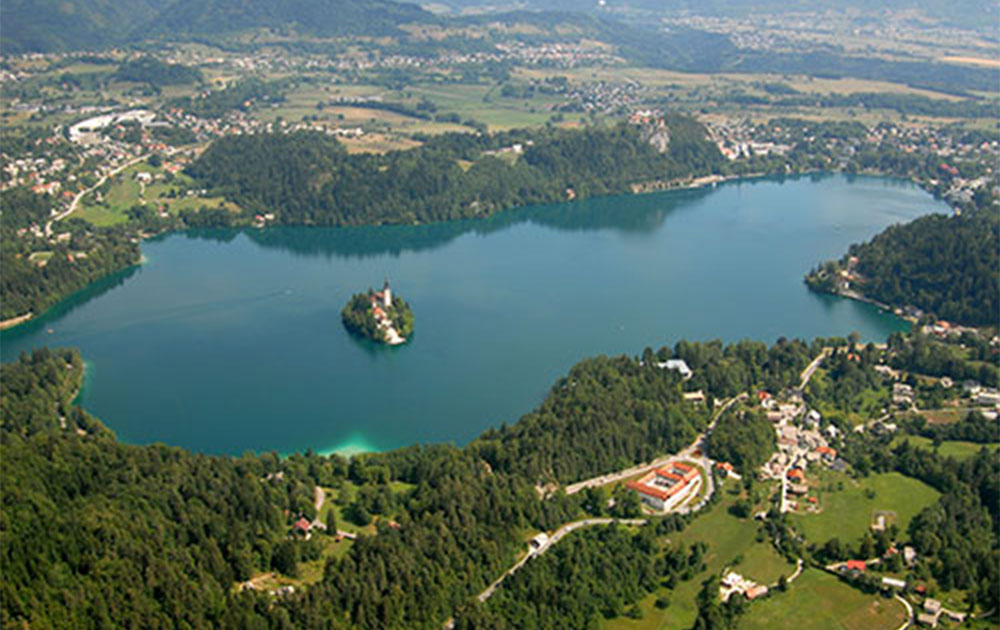 A lake seen from above surounded by trees and buildings