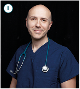 Carlos Jaramillo smiles at the camera. He is wearing blue scrubs and has a stethoscope hanging around his neck.